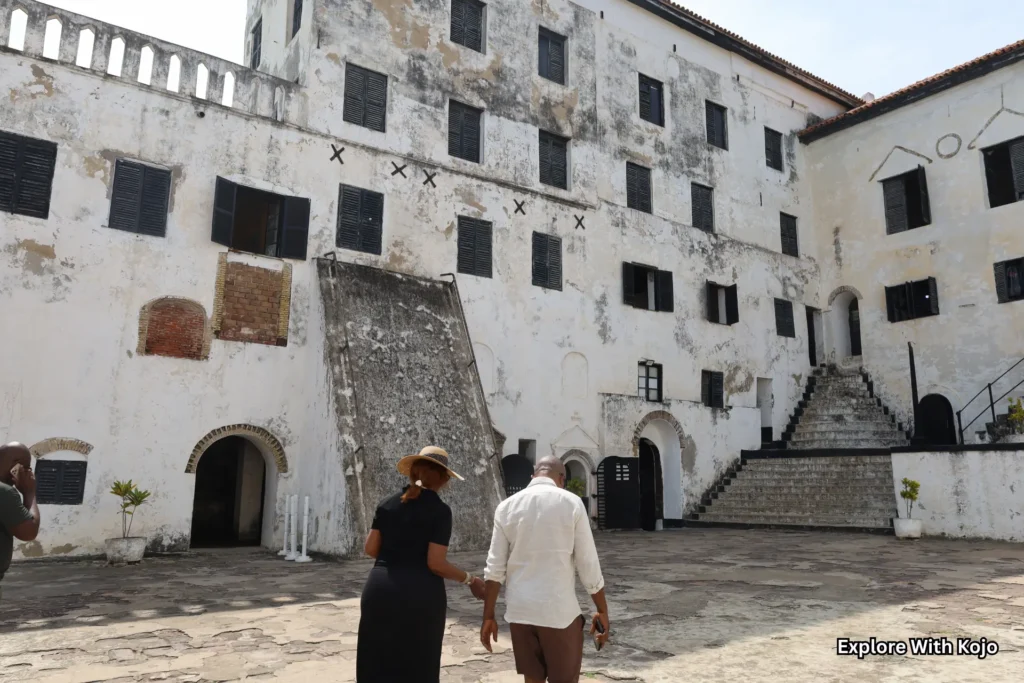 Visitors walking through the historic courtyard of Elmina Castle in Ghana.