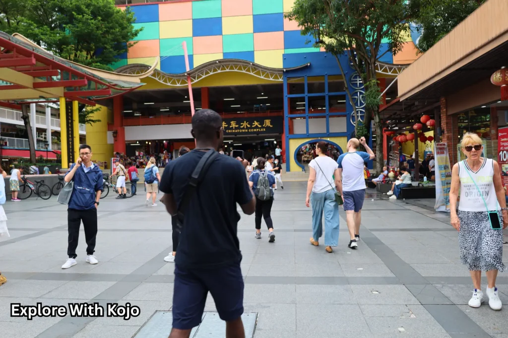 Kojo walking through Chinatown Complex in Singapore surrounded by locals and tourists, highlighting how travel fosters cultural understanding