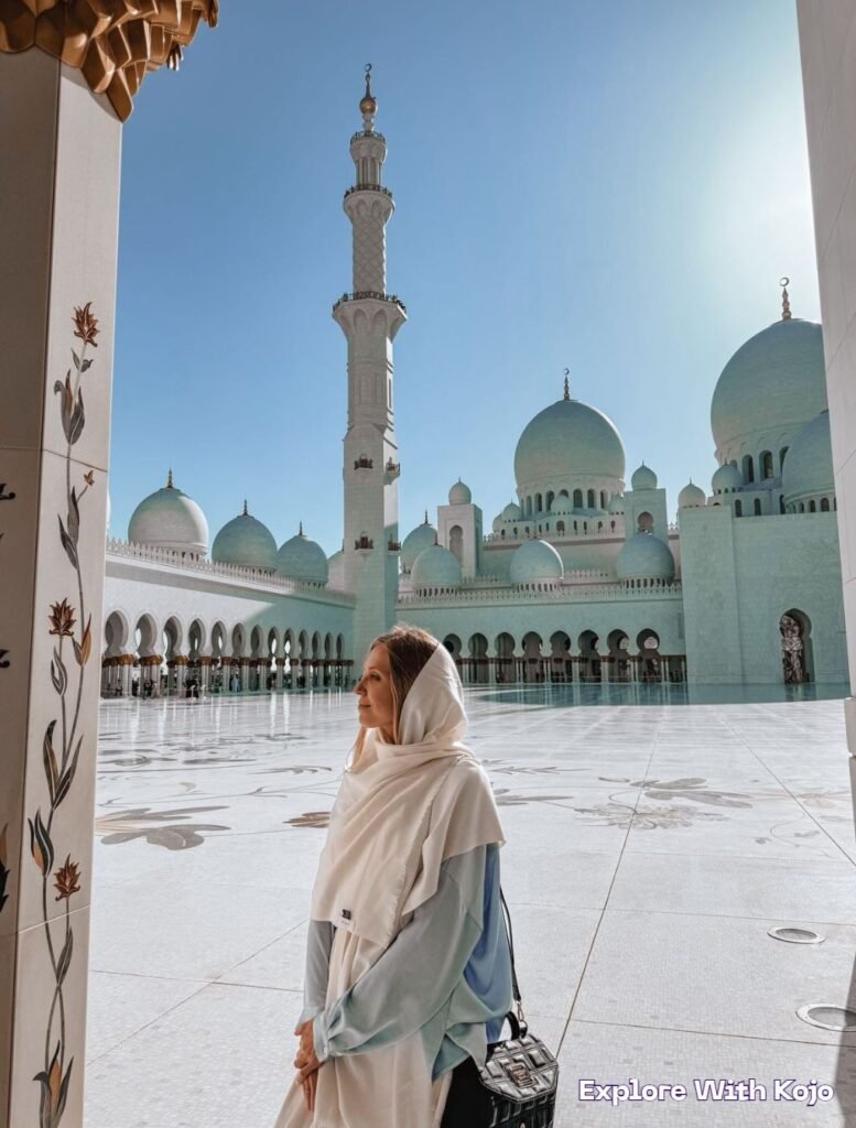 A female traveler in a headscarf admiring the Sheikh Zayed Grand Mosque in Abu Dhabi, UAE.