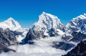 Snow-covered Himalayan mountains with peaks above the clouds under a clear blue sky