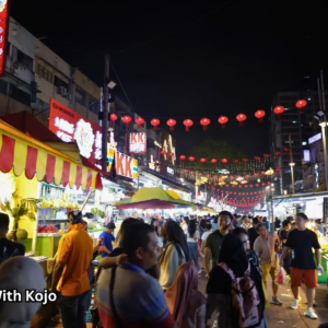 Tourists walking along Jalan Alor Night Market under red lanterns