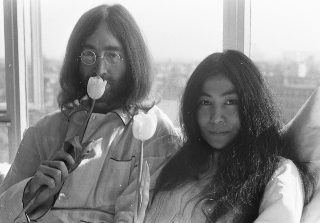 John Lennon and Yoko Ono holding tulips together in a candid black-and-white photo