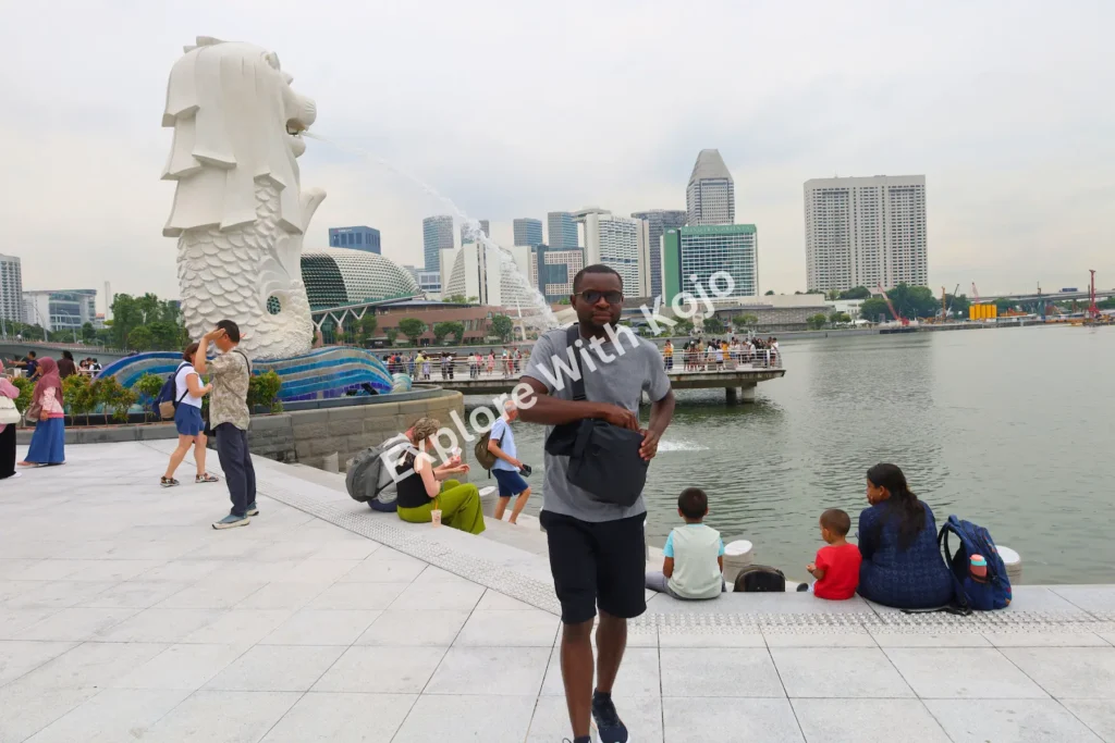 Kojo standing in front of the Merlion statue at Merlion Park in Singapore with skyline views