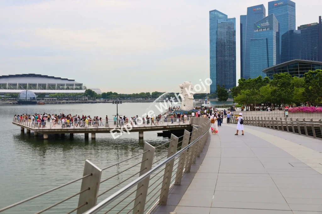 Wide view of Merlion Park in Singapore captured by Kojo showing Merlion statue, crowds, and Marina Bay skyline