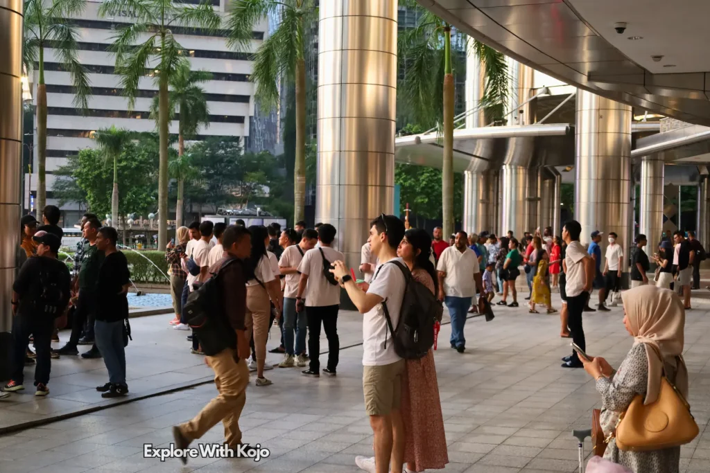 People walking outside tall office towers in Kuala Lumpur.