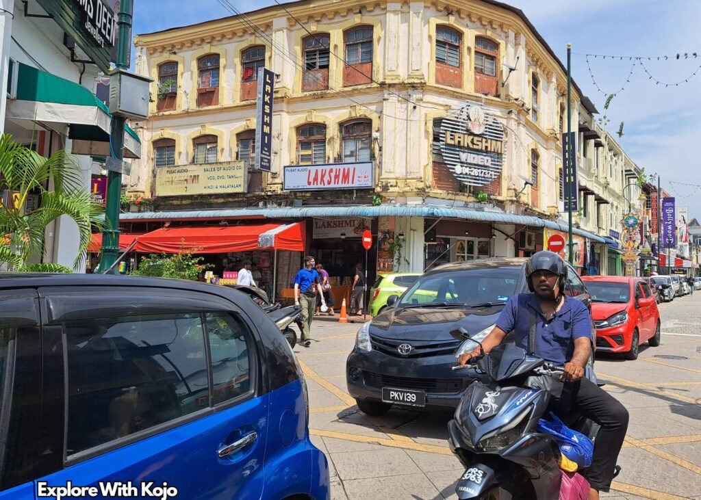 Busy street scene in Little India, Penang with shops, cars, and people