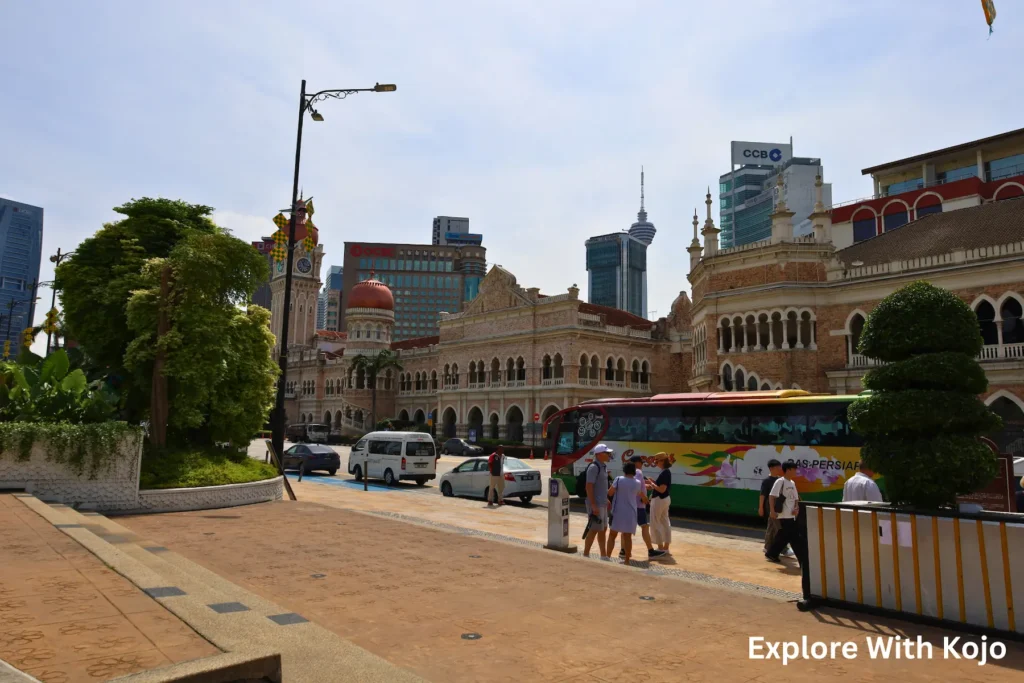 Tourists walking through Merdeka Square in Kuala Lumpur with colonial buildings in the background