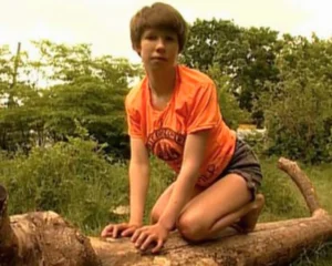 Oxana Malaya, the Ukrainian feral child, crouching outdoors in an orange shirt.