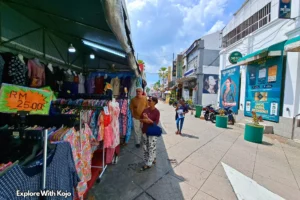 Tourists browsing colorful clothes at a street market in Little India, Penang, Malaysia