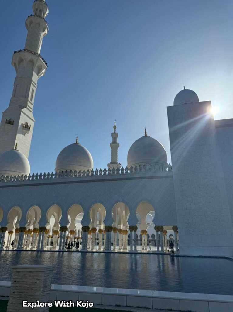 Sheikh Zayed Grand Mosque in Abu Dhabi with sunlight shining over its domes and minaret