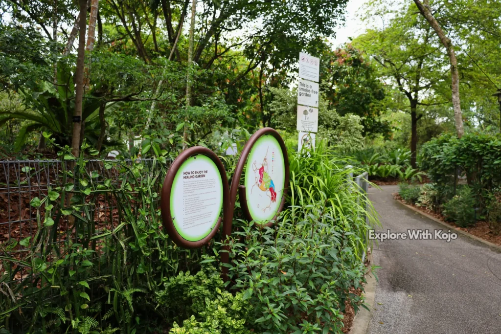 Pathway inside Singapore Botanic Gardens with signboards for visitors.