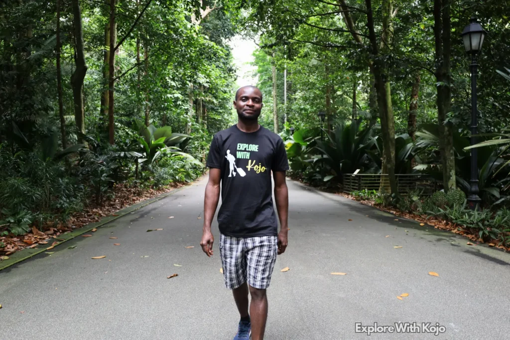 Tourist walking through a lush greenery path at Singapore Botanic Gardens.