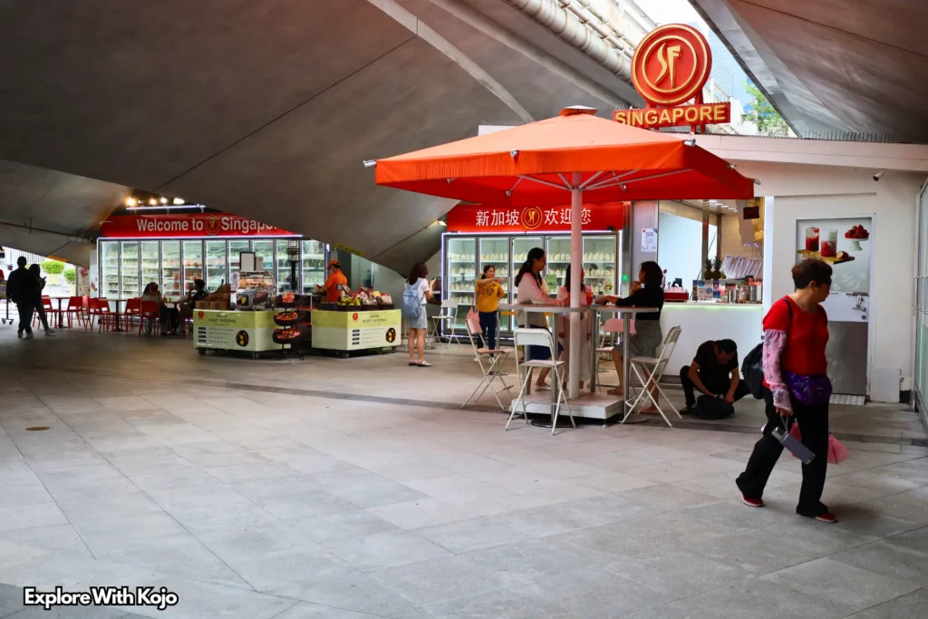 Small food and drinks stalls at Merlion Park in Singapore with people sitting and walking nearby