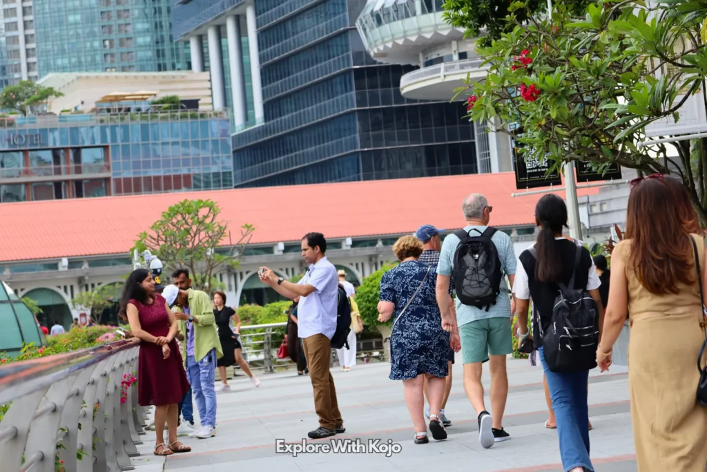 People walking along the Marina Bay promenade in Singapore with skyscrapers in the background.