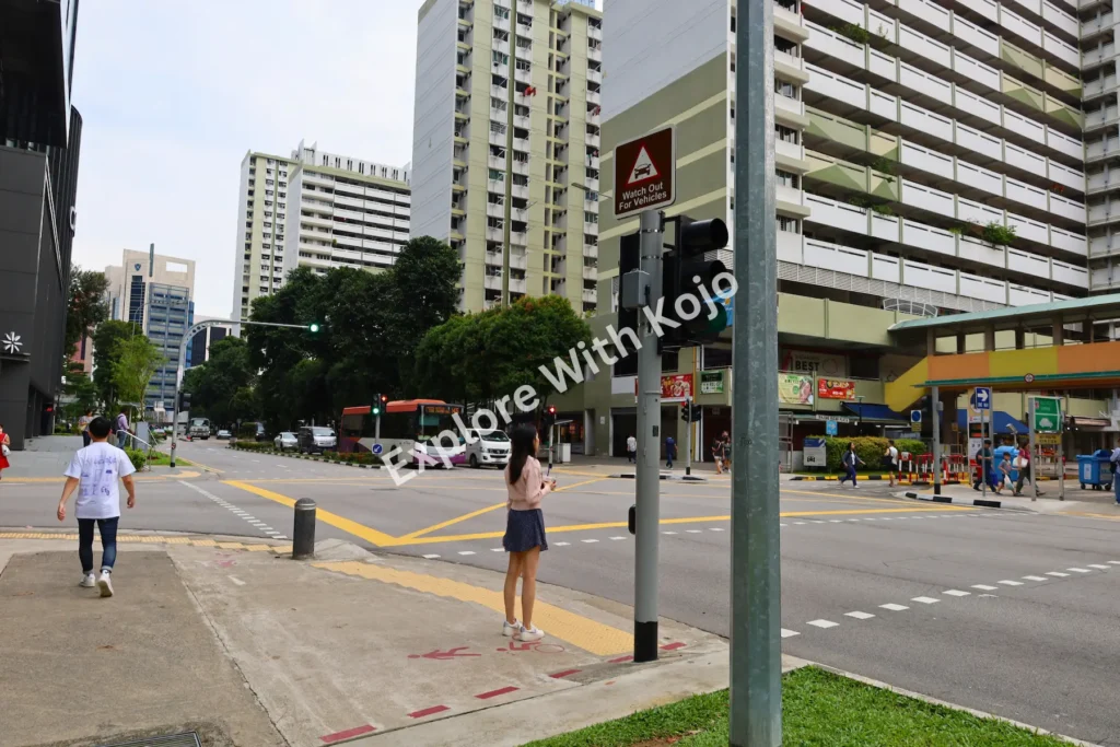 Pedestrians crossing the road near HDB flats in Singapore.