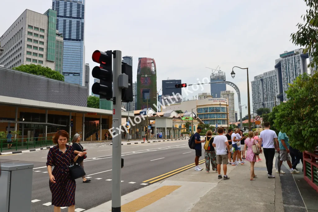 ourists walking along a busy street in Singapore’s city center with skyscrapers in the background.