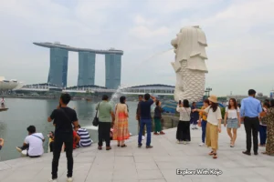 Tourists at the Merlion Park in Singapore with Marina Bay Sands in the background