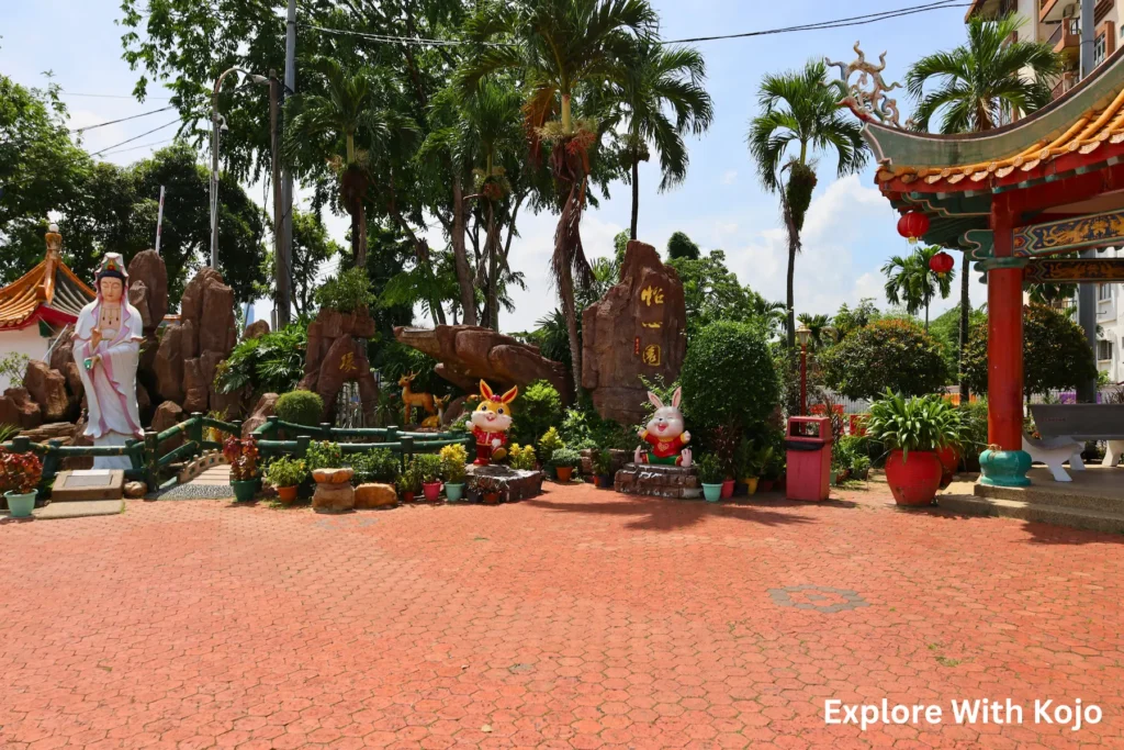 Wide view of the courtyard at Thean Hou Temple in Kuala Lumpur with statues and greenery.