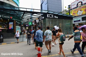 People walking through Bukit Bintang in Kuala Lumpur wearing light summer outfits like shorts, T-shirts and sandals.