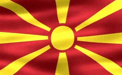Flag of North Macedonia with red field and yellow sunburst.