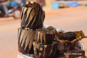 Stacked wrapped African black soap bars in Tamale Ghana with one unwrapped on a wooden board