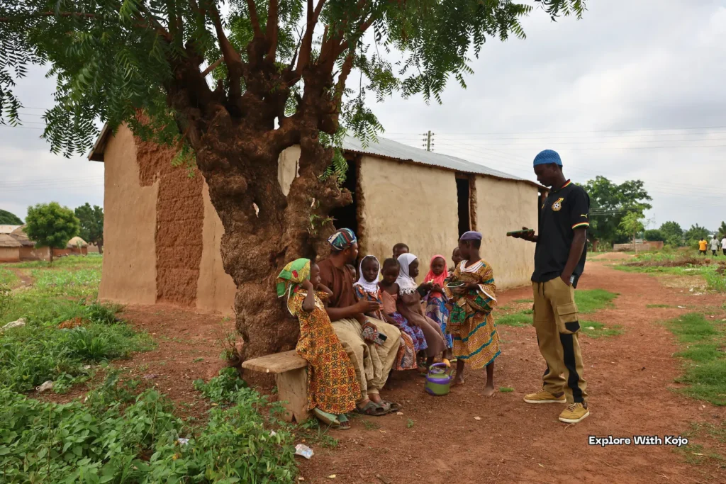 Man teaching children outdoors in an African village.