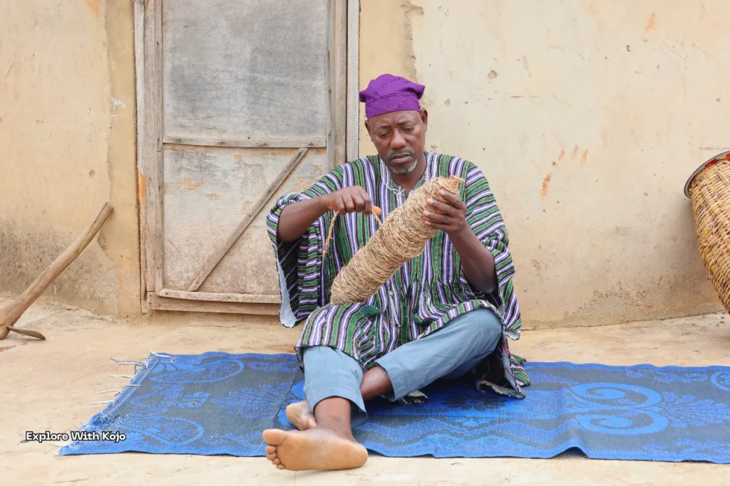 Man weaving a basket in front of his home in Ghana.