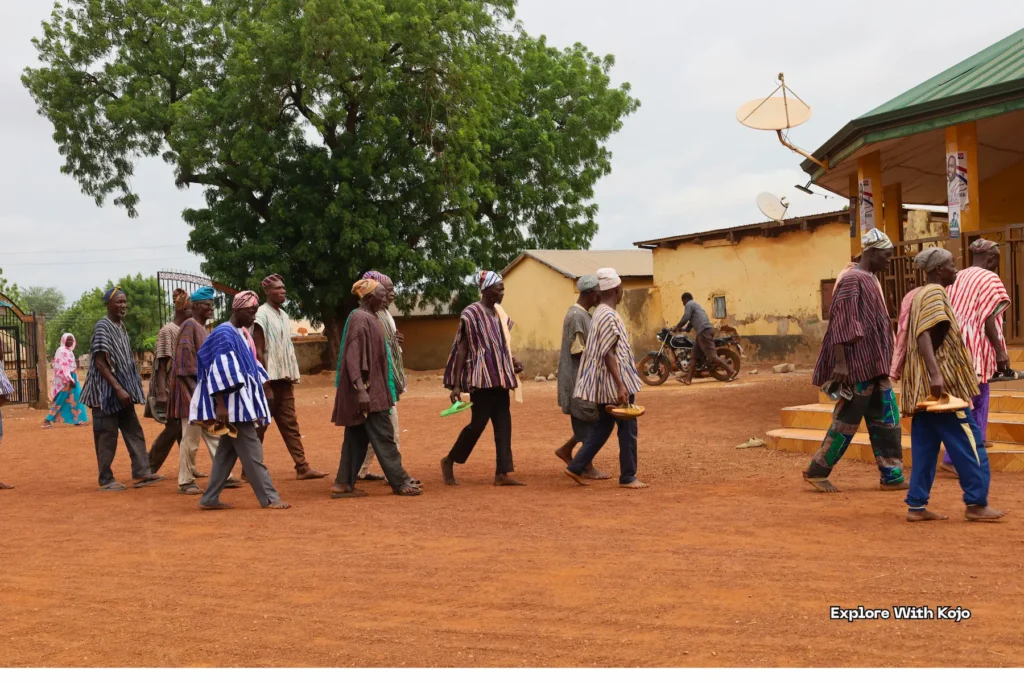 Group of African men walking past village buildings.
