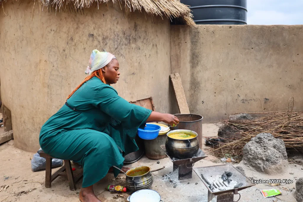 Woman cooking local food outdoors in a Ghanaian village.