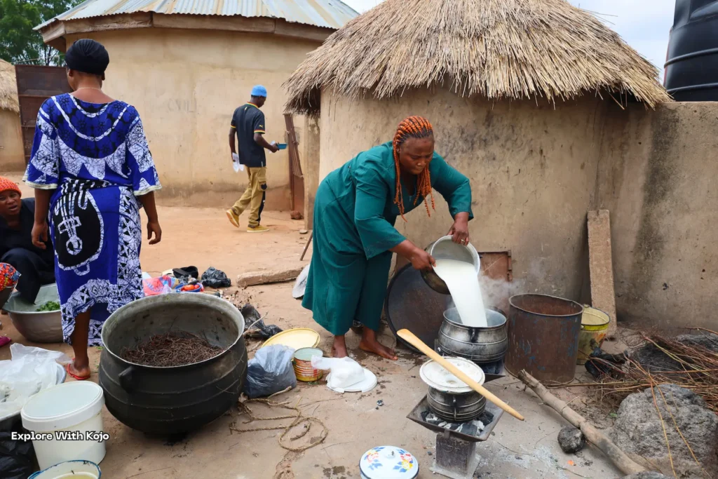 Woman stirring food in a large pot outdoors.