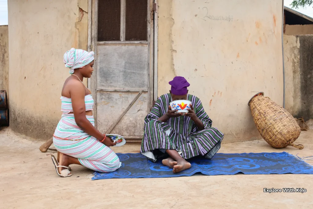 Women having a conversation outside a mud house.