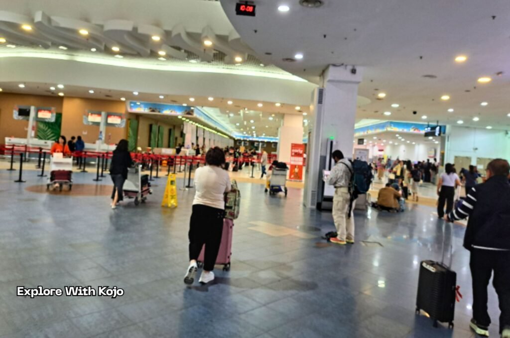 Travelers with suitcases standing near the check-in counters inside an airport, illustrating the rush and uncertainty after missing or almost missing a flight.