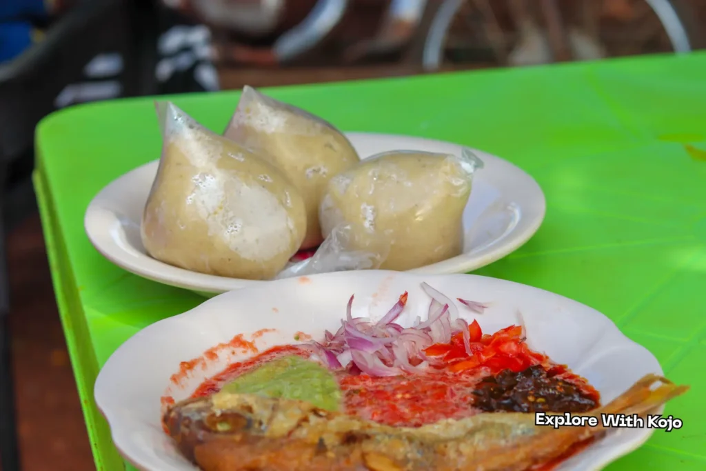 Banku and fish served with spicy red pepper, green sauce, and onions.