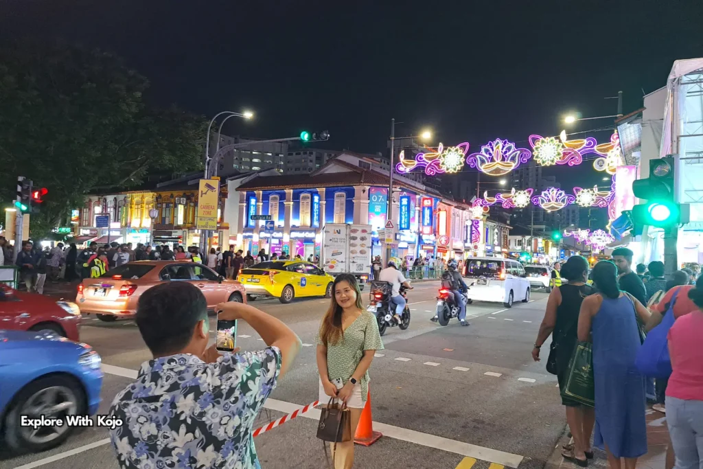 Tourists posing for photos under colorful Deepavali lights at Little India Singapore.