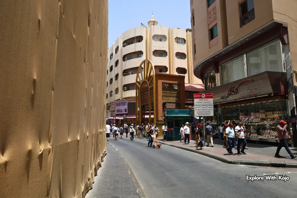 Narrow lane leading to the Gold Souk in Deira with people walking and shops on both sides