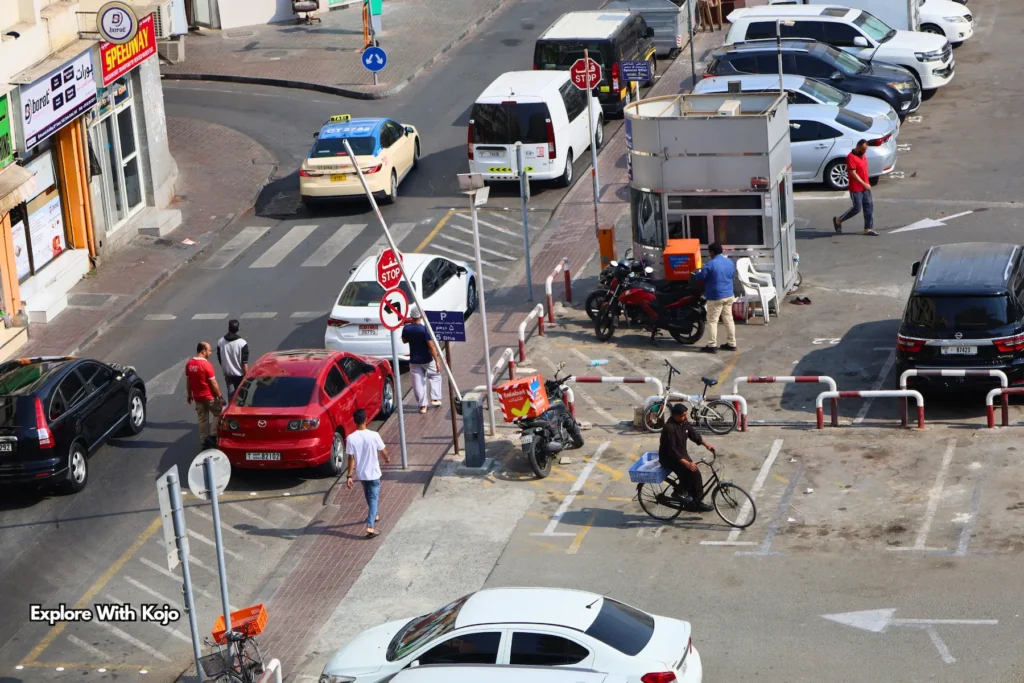 Busy Deira street with vendors, taxis, and delivery riders