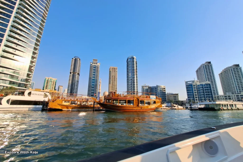Traditional dhow boat cruising along Dubai Marina with modern skyscrapers in the background