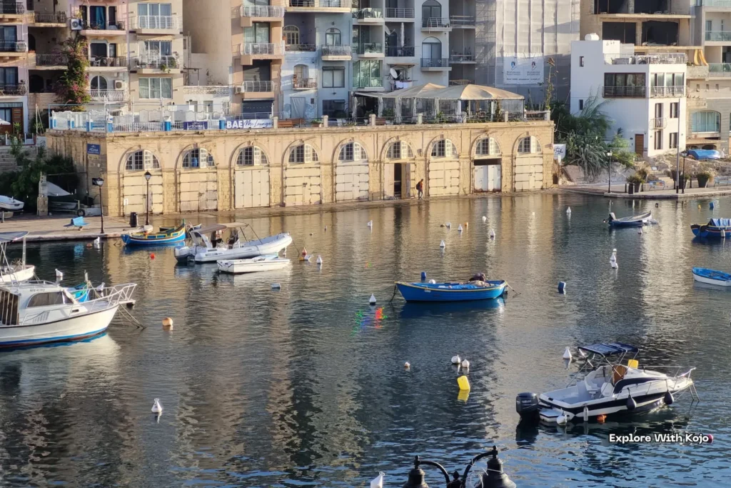 Boats docked along a waterfront with historic buildings in Malta, a Eurozone country.