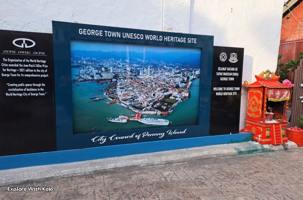Photo taken for Explore With Kojo of the George Town UNESCO World Heritage Site sign with aerial view of Penang Island, Malaysia.