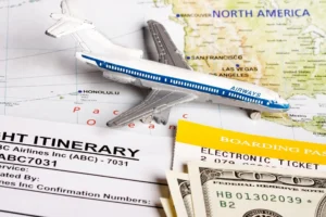 A toy airplane on a world map with a boarding pass, flight itinerary, and US dollar bills symbolizing cheap flight booking.