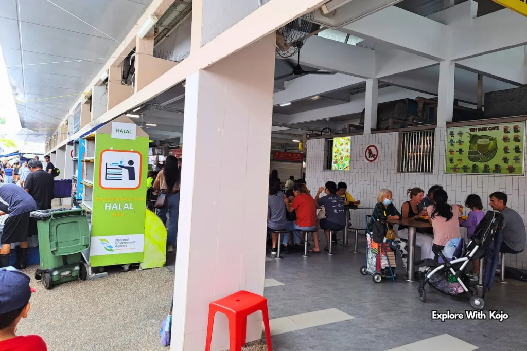 Diners seated in a covered area near a Pasar Malam in Singapore.