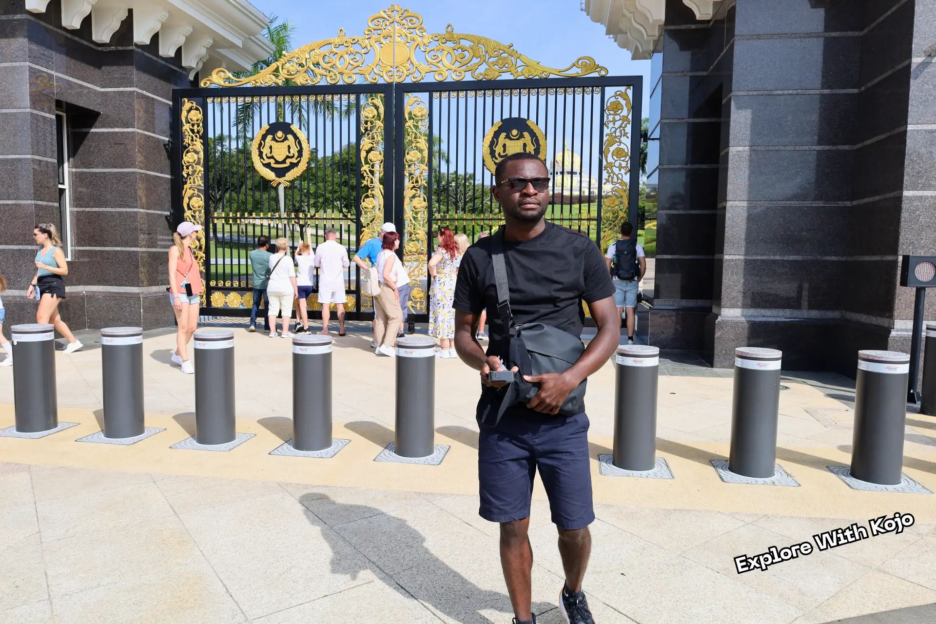 Kojo Enoch standing in front of the gates of the Istana Negara (National Palace) in Kuala Lumpur, Malaysia