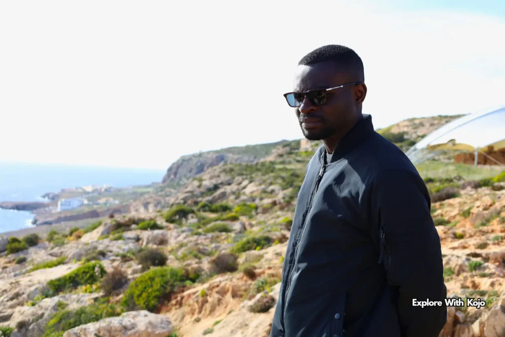 traveler Kojo standing on cliff overlooking Qrendi coast and Blue Grotto Malta