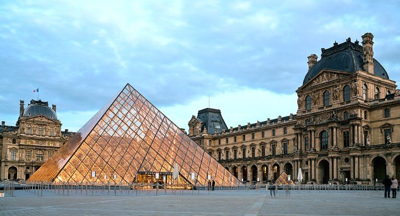 Paris with its glass pyramid and visitors outside.