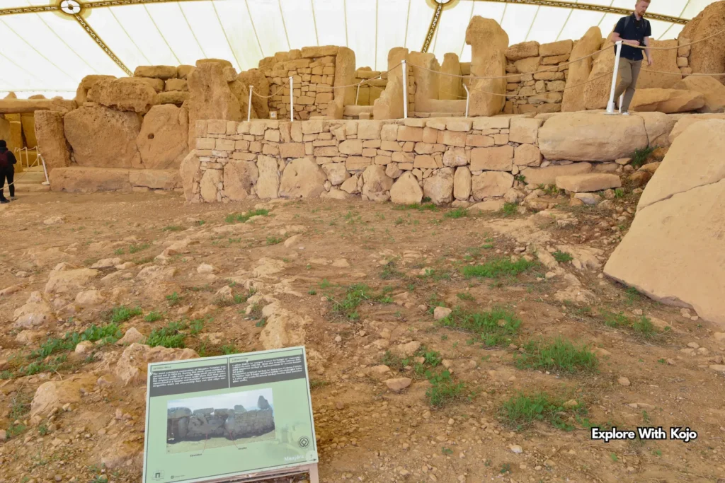 visitor walking past restored walls of Mnajdra temple under canopy