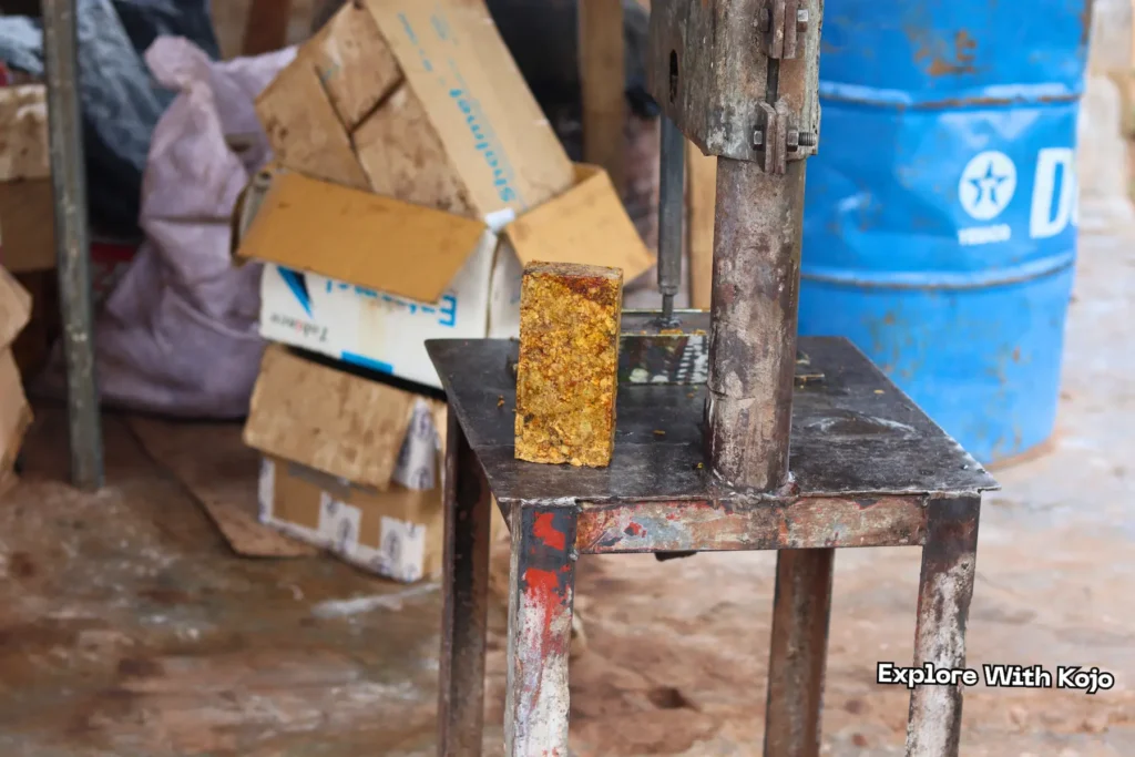 Metal mold pressing African black soap block in a workshop in Tamale, Ghana
