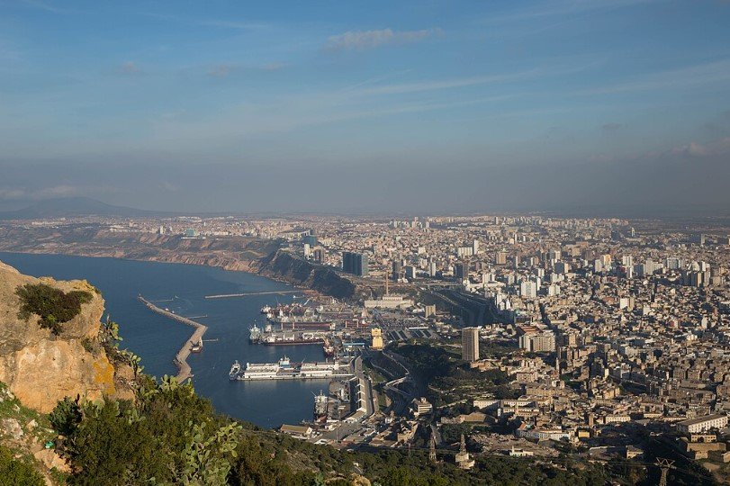 Oran city waterfront in Algeria with coastal buildings and sunset. 