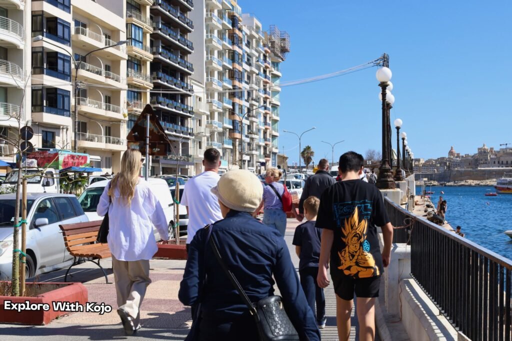 People walking along the seafront promenade in Sliema, Malta on a sunny day
