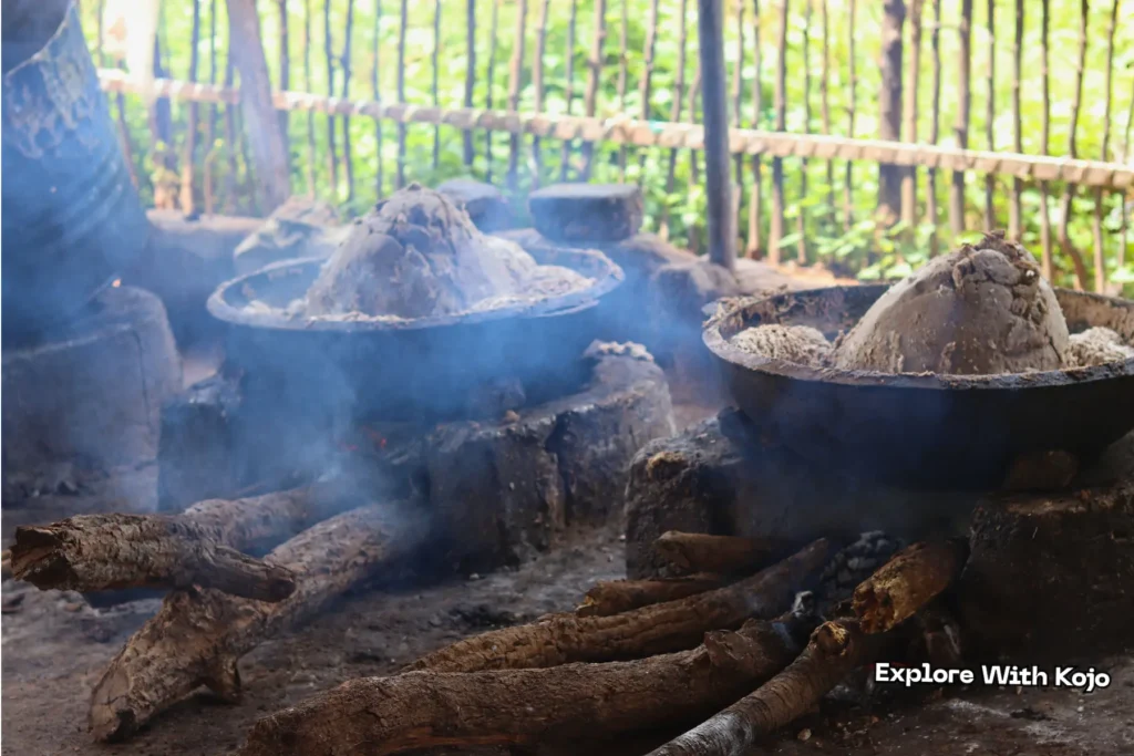 Multiple metal pots heating African black soap mixture in a rural Ghanaian workshop