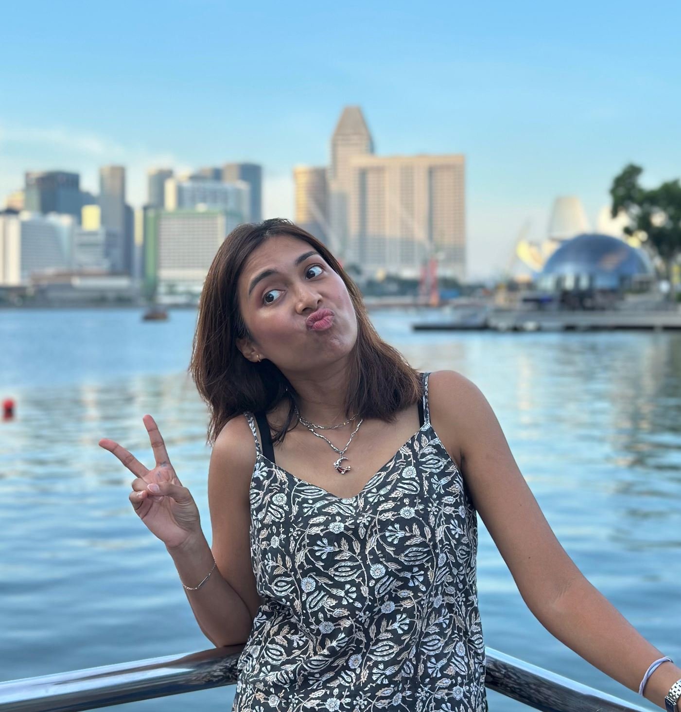 Sabrina Chitty, contributor and interviewer for Explore With Kojo, posing by the Singapore waterfront with the city skyline in the background